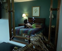 a woman is sitting on a bed in a hotel room
